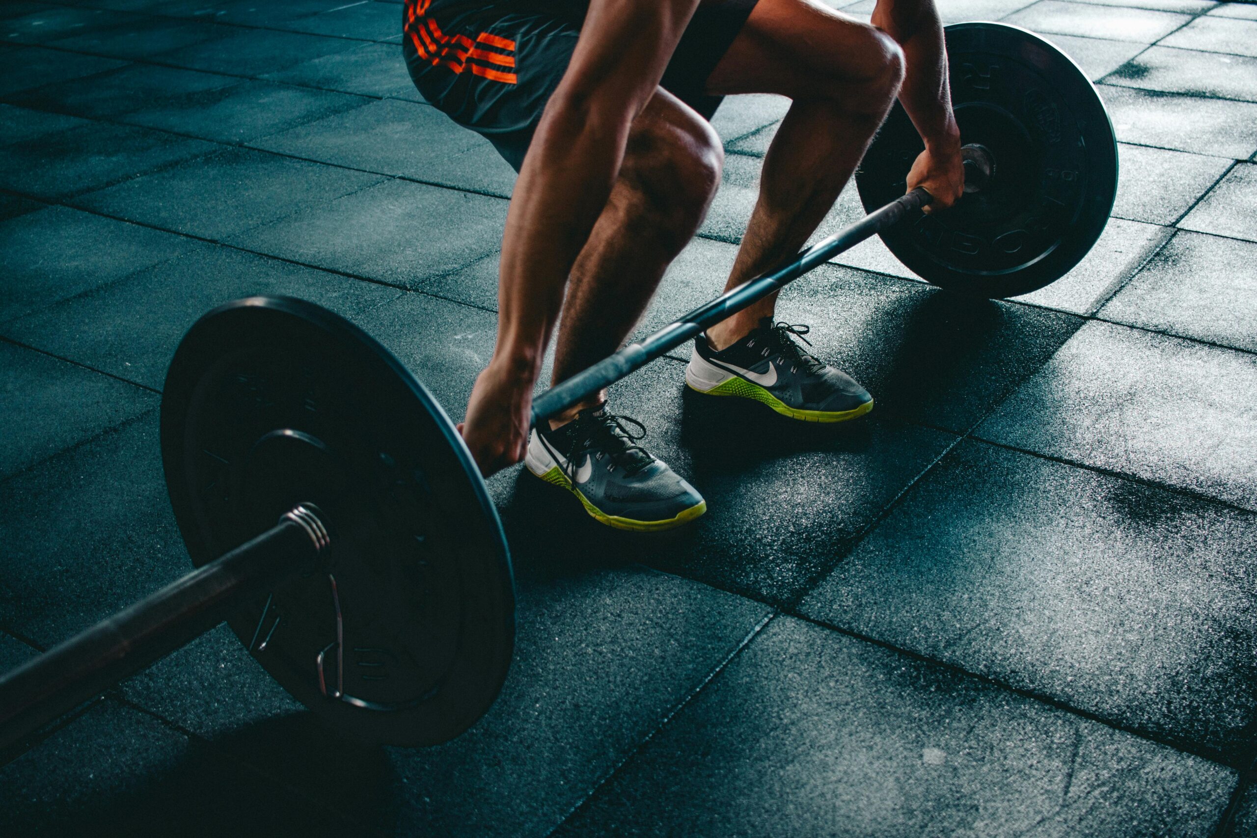 ジムでバーベルスクワットをする男性。効率的な全身運動でダイエット。
